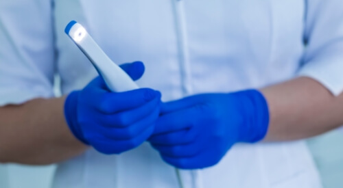 Dentist holding a thin white intraoral camera