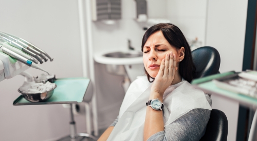 Woman holding her cheek in pain while visiting emergency dentist