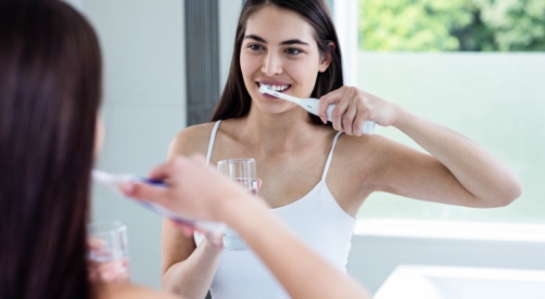 Woman smiling while brushing her teeth