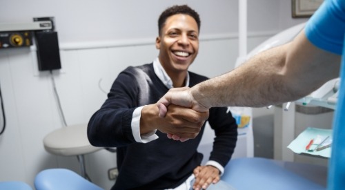 Smiling man shaking hands with his dentist