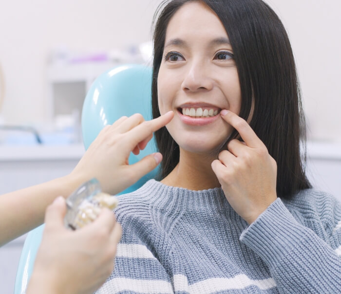 Dental patient pointing to her smile with dental implants in Santa Fe