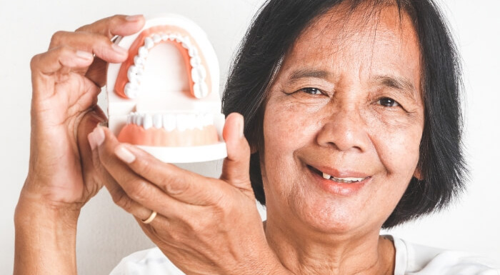 Smiling woman holding a set of dentures