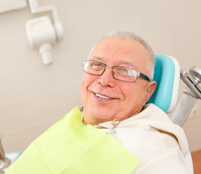 Senior man smiling in dental chair after restorative dentistry in Santa Fe