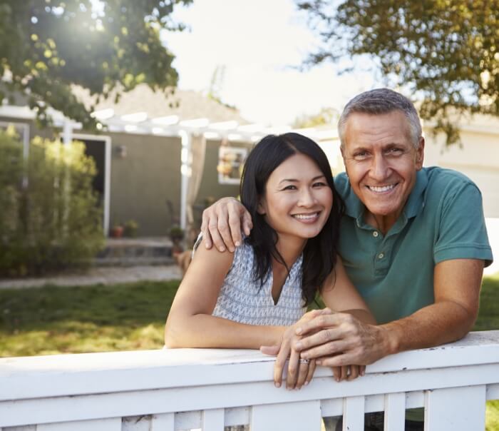 Man and woman smiling in their front yard after receiving dental services in Santa Fe