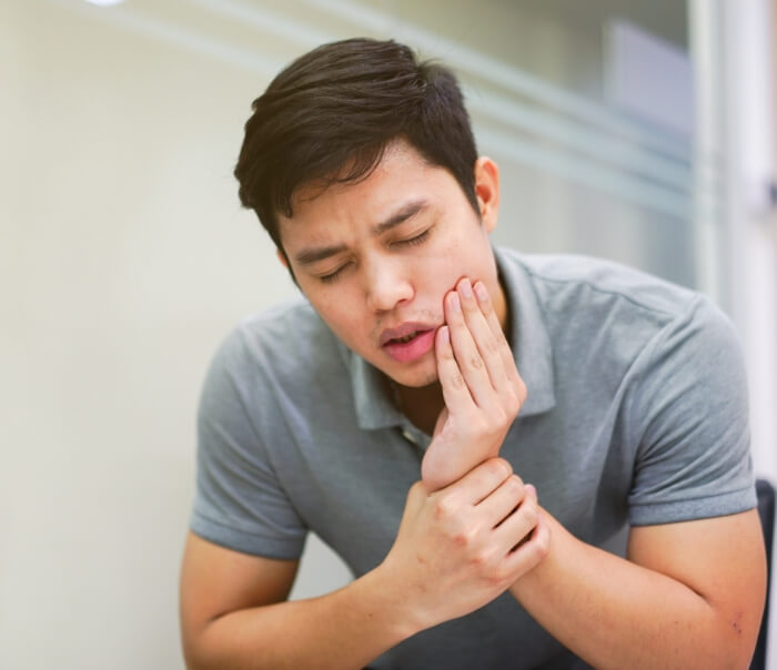 Man wincing and holding his jaw in pain before T M J treatment in Santa Fe