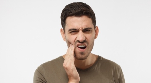 Man holding the side of his jaw in pain