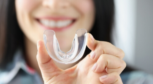 Smiling woman holding a clear dental tray